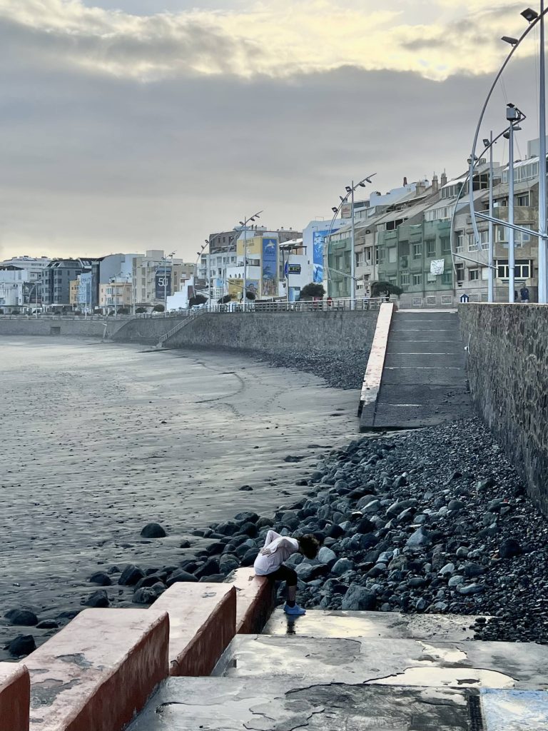 Woman in pain leaning over on the steps by the beach
