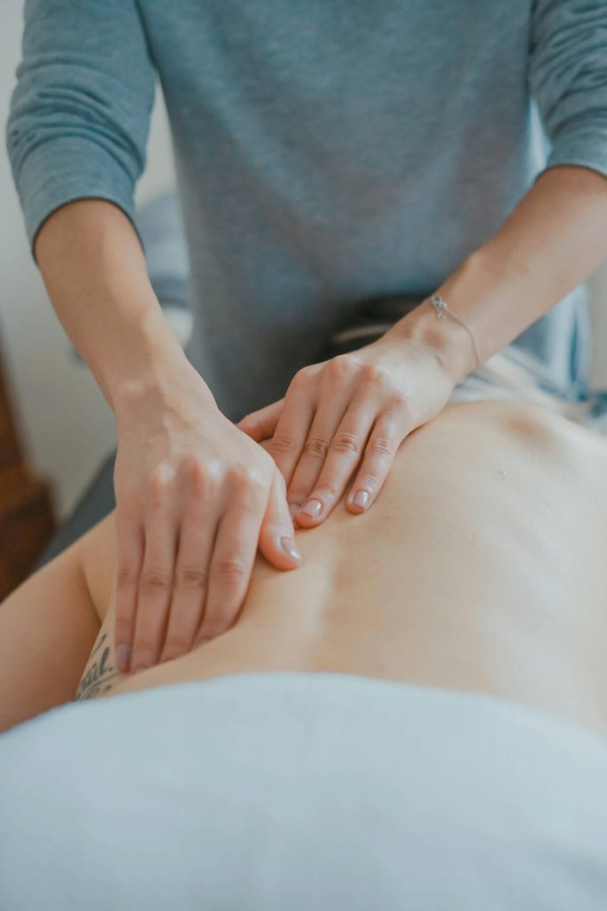 Body work massage woman touching the upper back of a patient performing a type of frequency healing therapy