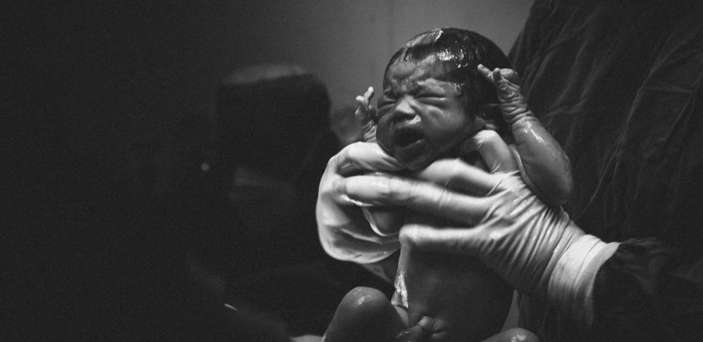 A baby being born in black and white, birth story, healing and health