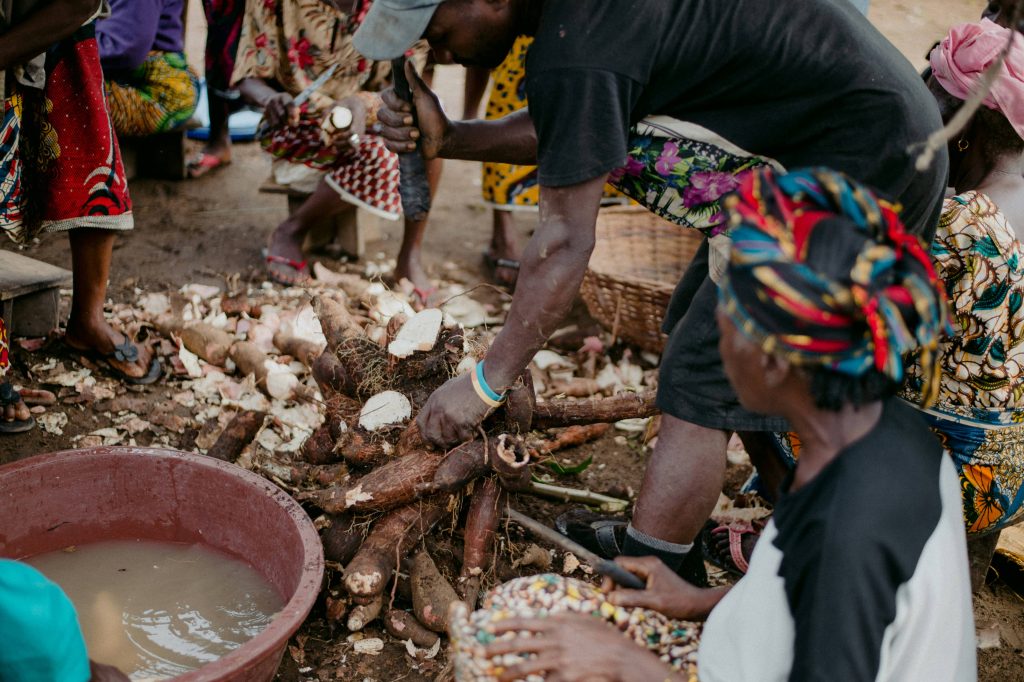 African man cutting and washing yuca root at a market