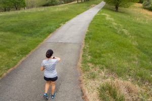 Woman grabbing back of head while on a running path